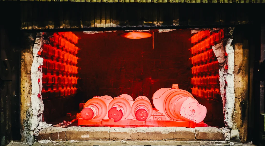 Alloy steel crane wheel billets glowing red hot in heat treating furnace at UTEC Industrial