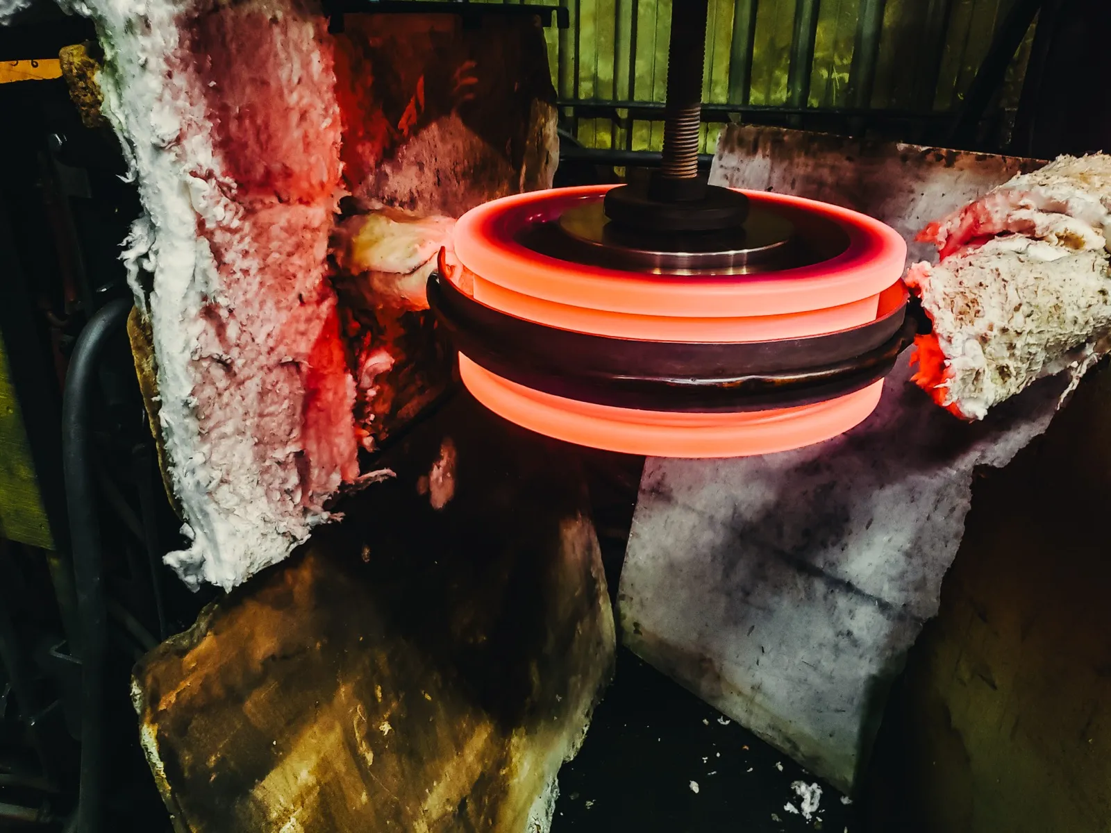 Induction hardening coil glowing orange-red around crane wheel tread at UTEC Industrial
